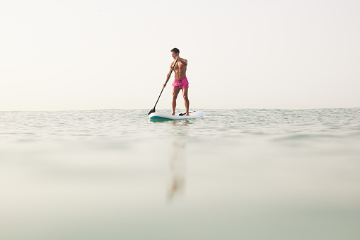 A fit middle-aged man rowing on a paddleboard