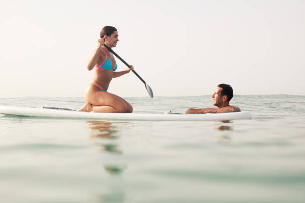 istock Man and woman enjoying time together on a paddleboard. 1665616892