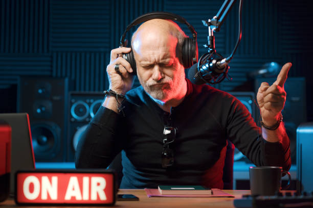 Radio host listening to music Radio host working in the radio broadcasting studio, he is on air and enjoying the music old person listening to radio stock pictures, royalty-free photos & images