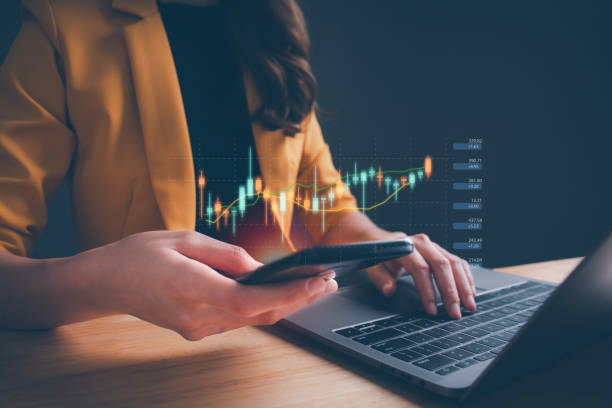 Businesswoman or trader using smartphone, showing a growing virtual hologram stock on computer laptop. Concept of planning and strategy, Stock market, Business growth, progress, trading or success.
