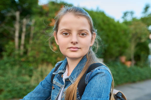 headshot portrait 10 years old girl with backpack outdoor, looking at camera - 10 11 years child human face female imagens e fotografias de stock