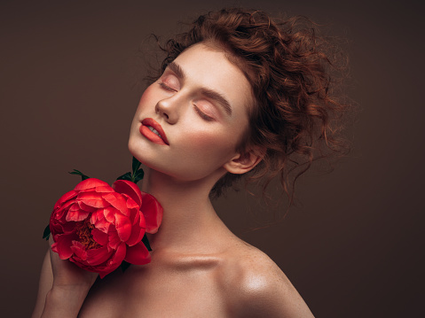 A beautiful woman laying in a colourful bed of red roses and other flowers