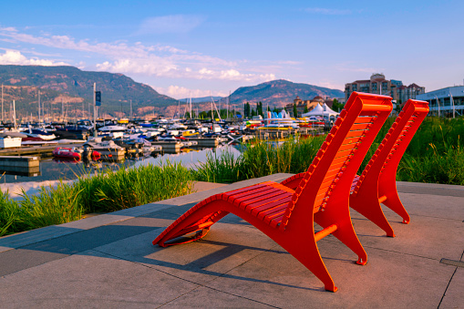 Two red adirondack benches or Muskoka chair on the deck  at Stuart Park marina on Okanagan Lake in British Columbia, western Canada