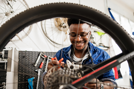 Smiling bicycle mechanic repairs mountain bike