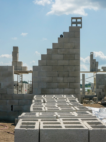 Concrete blocks stacked neatly in front of a section of exterior wall of a single-family house under construction in a suburban development on a sunny morning in southwest Florida