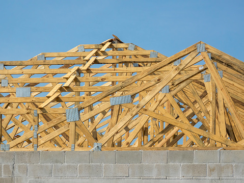 Detail of wooden trusses and truss plates for support of a new roof on a single-family house under construction in a suburban residential development in southwest Florida