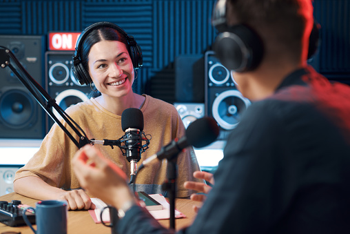 Young radio host interviewing a guest at the radio broadcast studio