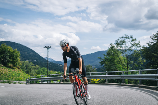 He is riding around a corner on the road