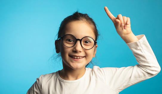 8 years old girl standing against blue background.