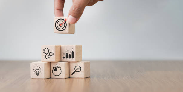 istock Business success goals Concept. Hand holding target board which printing on wooden cube block for creative and set up business objective target goal concept, blocks to create ideas, set target. 1665710072
