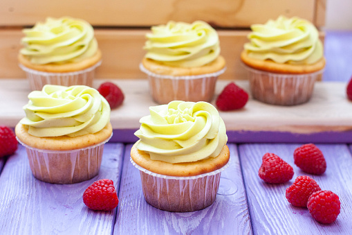 Preparation of pistachio cupcakes with fresh raspberry. Rustic wooden background, close up