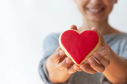 Woman showing heart shape cookie, close up.