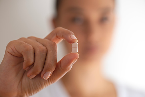 A woman holding a pill.
