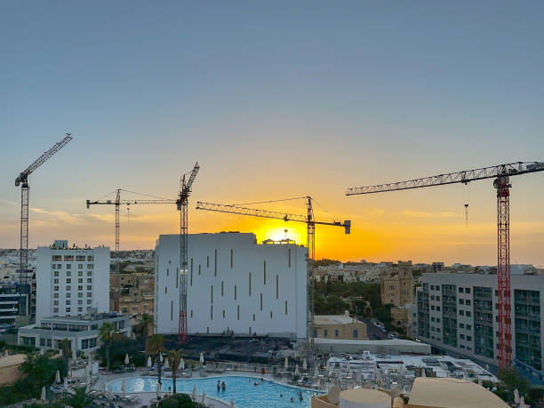 Silhouette of tower cranes on the skyline of St Julians, Malta, at sunset St Julians, Malta - 4 August 2023: Skyline of St Julians at sunset with tower cranes working on new hotel developments maltese silhouette stock pictures, royalty-free photos & images