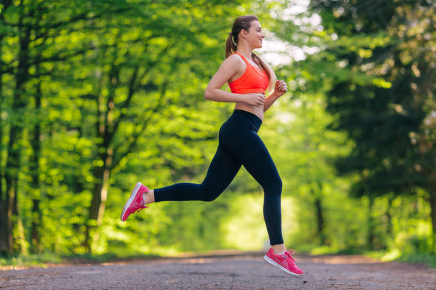 attractive young girl running in park. healthy lifestyle and sport concepts. girl is jogging on trees background. - running women jogging profile imagens e fotografias de stock