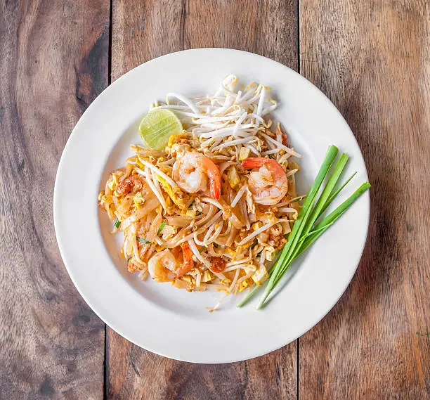 Pad Thai, stir-fried rice noodles, is one of Thailand's national main dish. Shot from top view - isolated on wooden table.