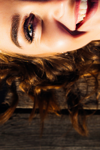 A close-up half-face of a girl lying on a wooden surface and smiling