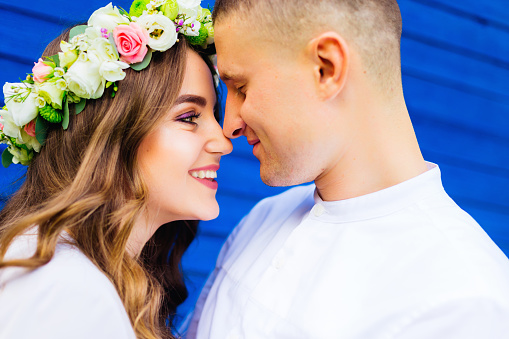 cute girl with a beautiful flower wreath on her head smiling to her boyfriend with closed eyes