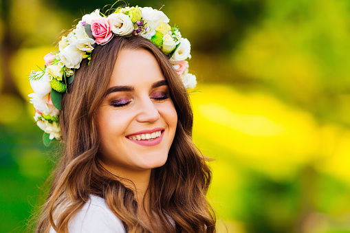Close-up of a beautiful girl with a wreath of flowers on her head that closed her eyes and smile