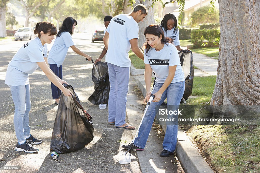 Volunteers cleaning up litter Team Of Volunteers Picking Up Litter In Suburban Street Cleaning Stock Photo
