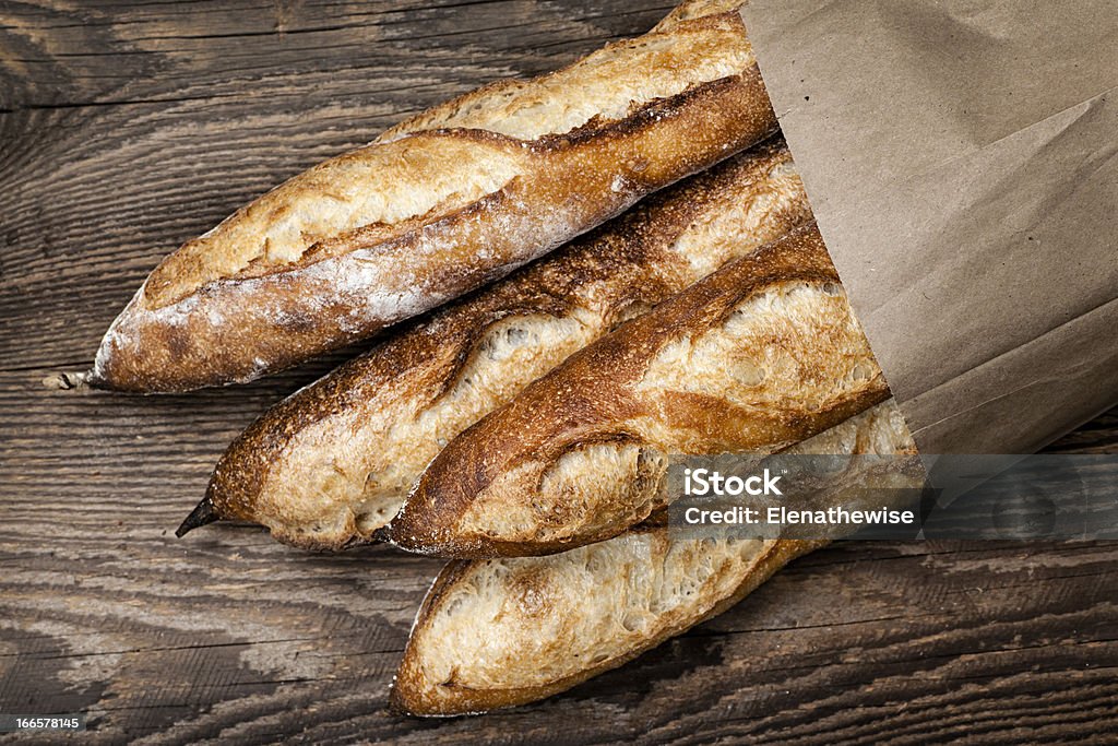 Baguettes bread Four baguette bread loaves in paper bag on wooden background Baguette Stock Photo