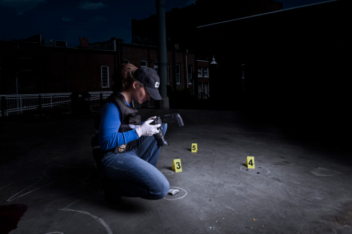 A female crime scene investigator (CSI) with evidence, camera and markers.