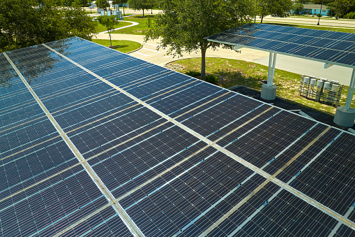 Aerial view of solar panels installed as shade roof over parking lot for parked cars for effective generation of clean electricity. Photovoltaic technology integrated in urban infrastructure.