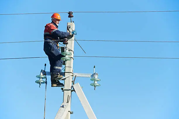 Photo of power electrician lineman at work on pole