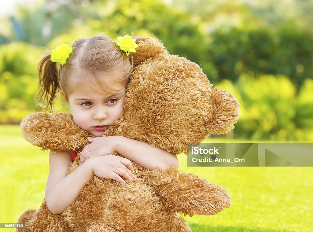 Sad girl with teddy bear Little cute sad girl holding in hands brown teddy bear, upset child spending time outdoors in spring time Child Stock Photo