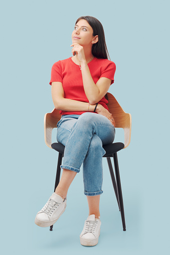 Portrait of young woman sitting on a chair and thinking