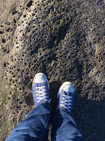 Person's point of view looking down on their shoes while standing on a rock.