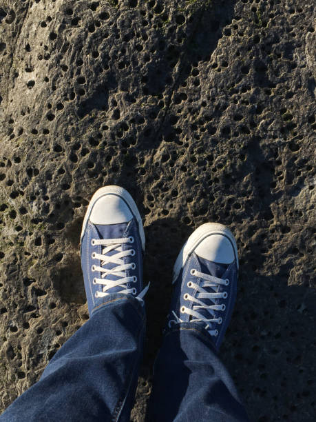 Person's point of view looking down on their shoes while standing on a rock.