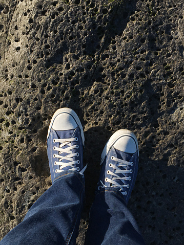 Person's point of view looking down on their shoes while standing on a rock.