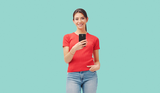 Young cute woman smiling and connecting with a smartphone