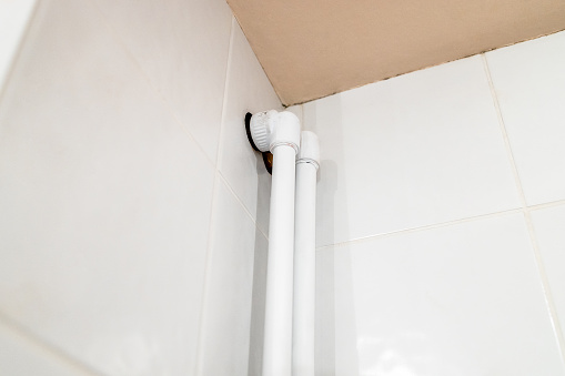 entry of polypropylene pipes at ceiling of bathroom on wall covered with ceramic tiles