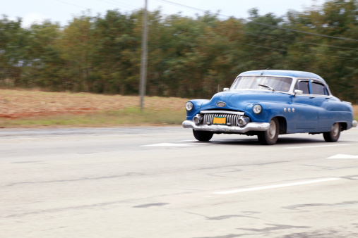 Old classic car drives by Cuban highway between Havana and Trinidad