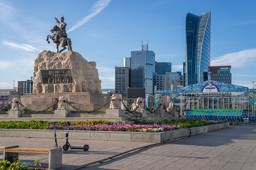 Ulaanbaatar, Mongolia - July 16, 2023: An equestrian statue of Damdin Sükhbaatar in Sukhbaatar Square is seen in front of office buildings and the Blue Sky Hotel.