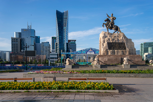 Ulaanbaatar, Mongolia - July 16, 2023: An equestrian statue of Damdin Sükhbaatar in Sukhbaatar Square is seen in front of office buildings and the Blue Sky Hotel.