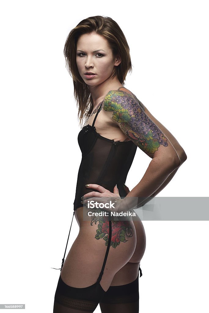 Woman with tattoo on arm standing sideways against white background A young woman with a tattoo on her arm standing sideways agains white background Adult Stock Photo