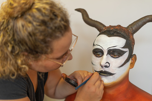 woman practicing body make-up on a model in a make-up school