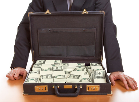 Business man standing next to open briefcase with money ,bribe concept