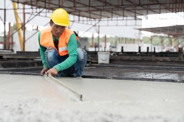 istock Asian male builder worker making levelling concrete floor to smooth at construction site. Construction worker uses long trowel spreading wet concrete pouring. Mason making smooth surface of concrete 1665902908