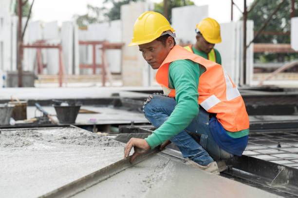 istock Asian male builder worker making levelling concrete floor to smooth at construction site. Construction worker uses long trowel spreading wet concrete pouring. Mason making smooth surface of concrete 1665903445