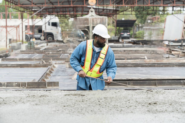 istock Construction worker uses long steel trowel spreading wet concrete pouring at precast concrete wall construction site. Worker or mason working or making smooth surface of concrete with equipment tool 1665904522