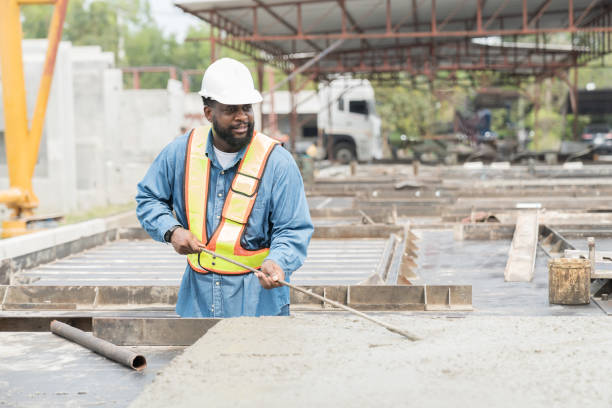 istock Construction worker uses long steel trowel spreading wet concrete pouring at precast concrete wall construction site. Worker or mason working or making smooth surface of concrete with equipment tool 1665905074