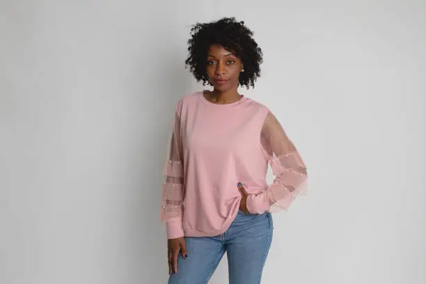 Black woman wearing a pink sweater looking at the camera