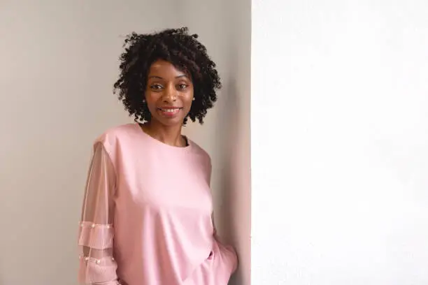 Black woman wearing a pink sweater looking at the camera