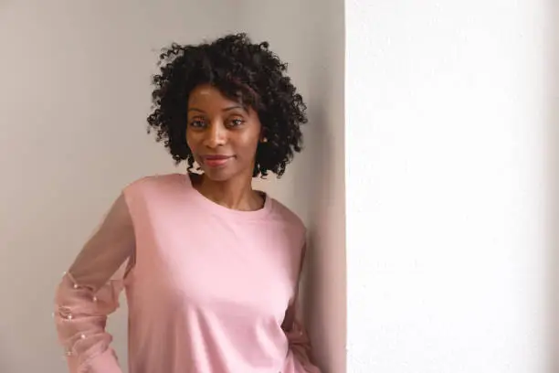Black woman wearing a pink sweater looking at the camera