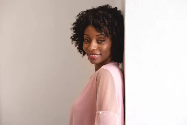 Black woman wearing a pink sweater looking at the camera