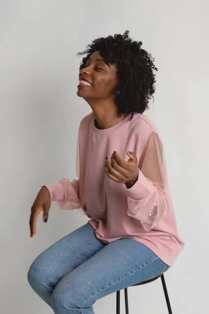 Black woman wearing a pink sweater laughing